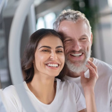 man and woman with great dental hygiene smiling in bathroom mirror