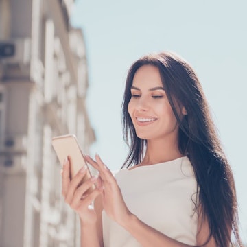 Woman with dermal fillers smiling looking at mobile phone