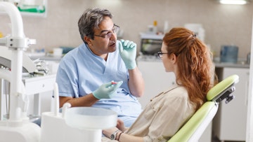 Male dentist talking to female patient in surgery