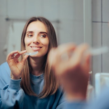 woman holding invisalign clear aligners looking in the mirror